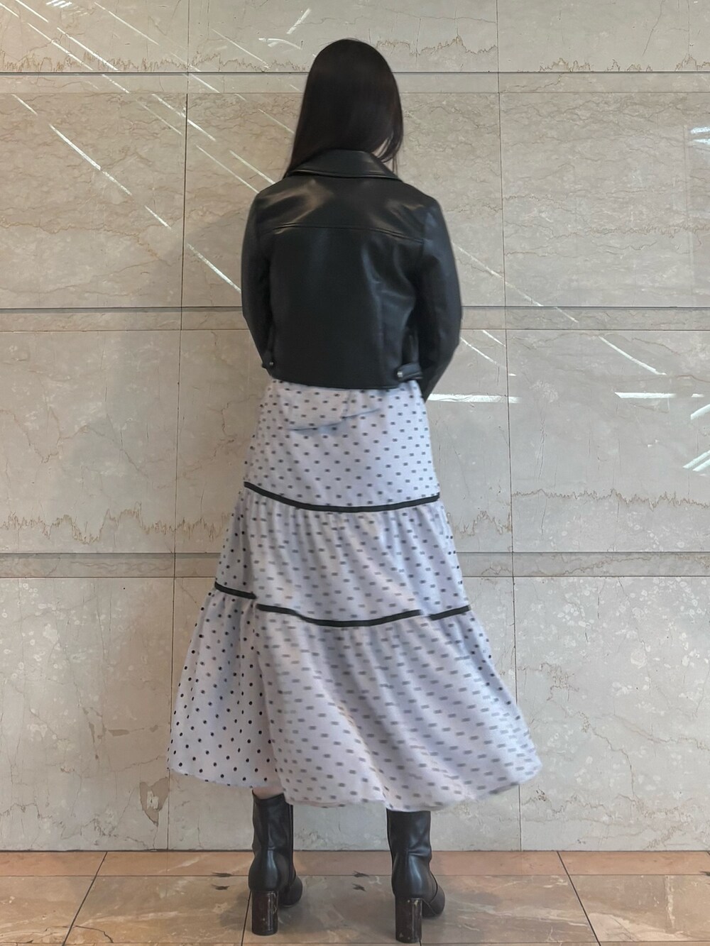 グレー系のワンピース、ブラック系のブーツ、ブラック系のライダースジャケットを着用したレディースの冬コーディネートの2枚目の写真