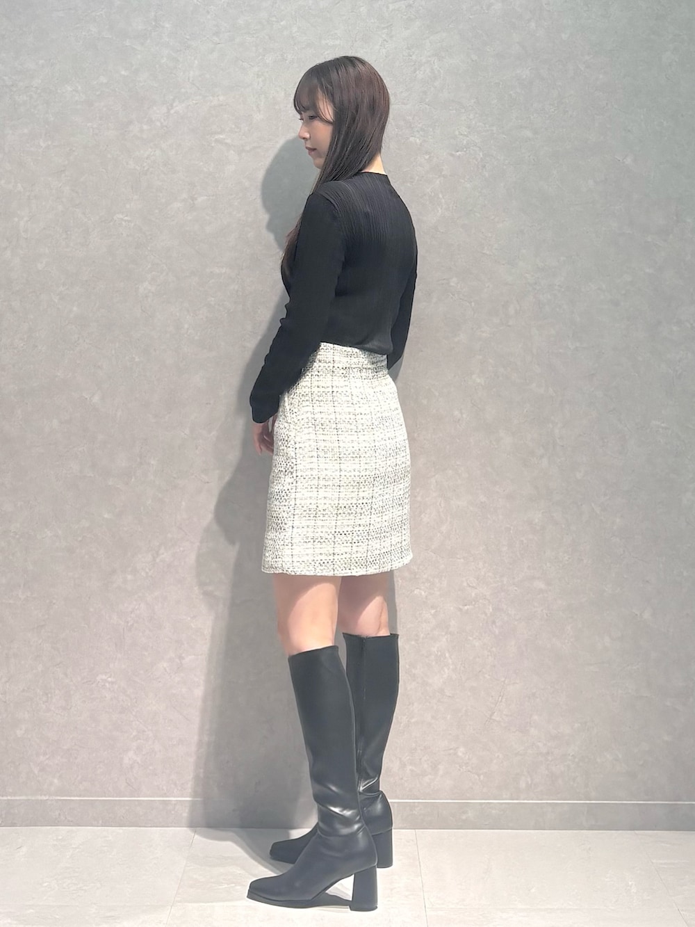 ホワイト系のスカート、ブラウン系のニット/セーター、ブラック系のブーツを着用したレディースの秋コーディネートの4枚目の写真