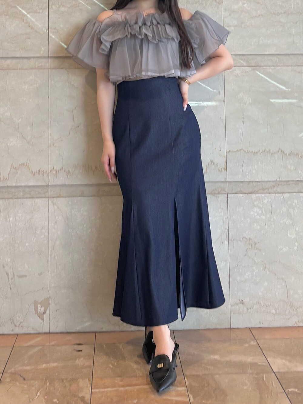 ブルー系のスカート、ブラック系のパンプス、グレー系のシャツ/ブラウスを着用したレディースの夏コーディネートの2枚目の写真