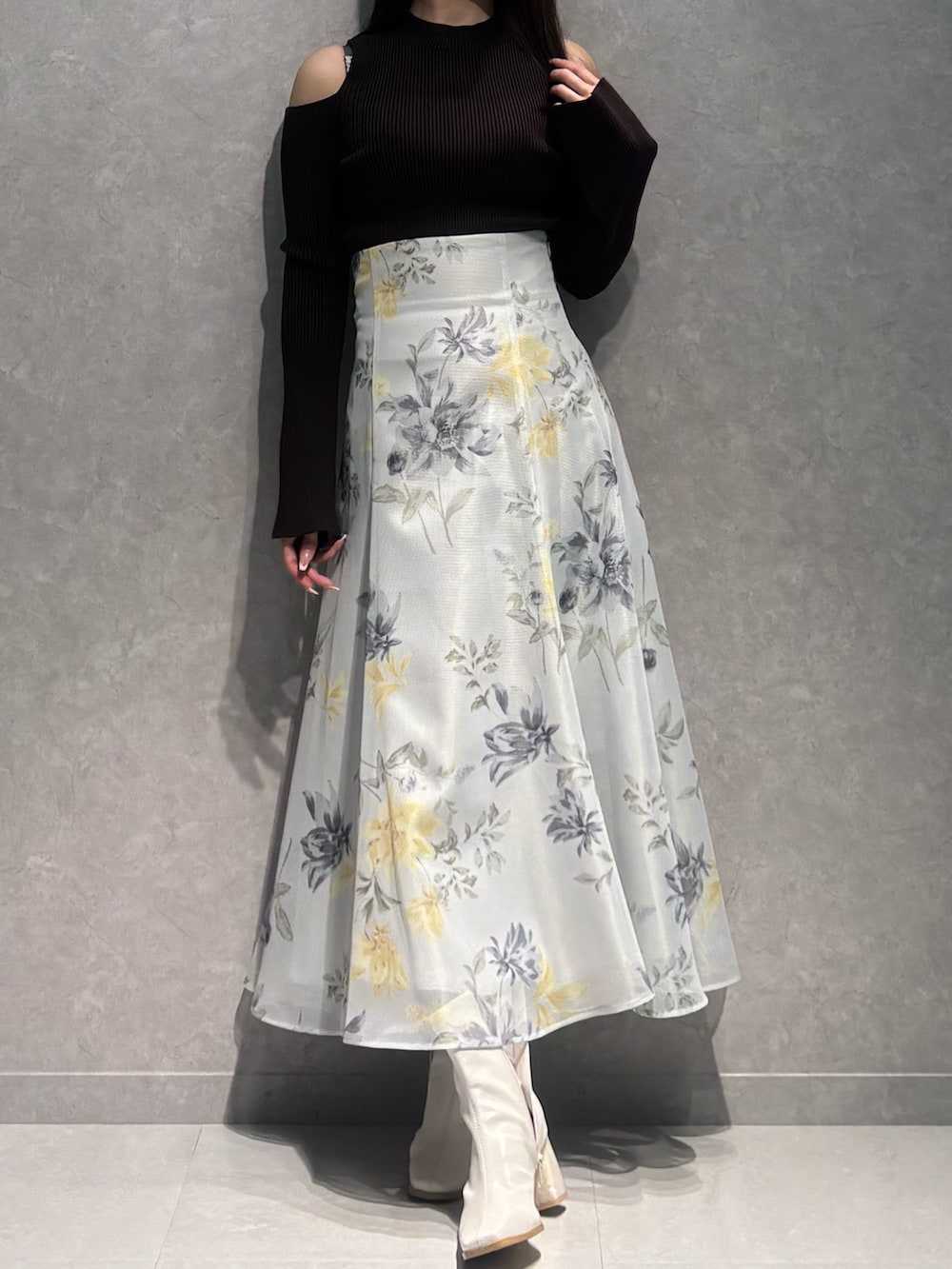 グリーン系のスカート、ブラウン系のニット/セーター、ホワイト系のブーツを着用したレディースの冬コーディネートの2枚目の写真