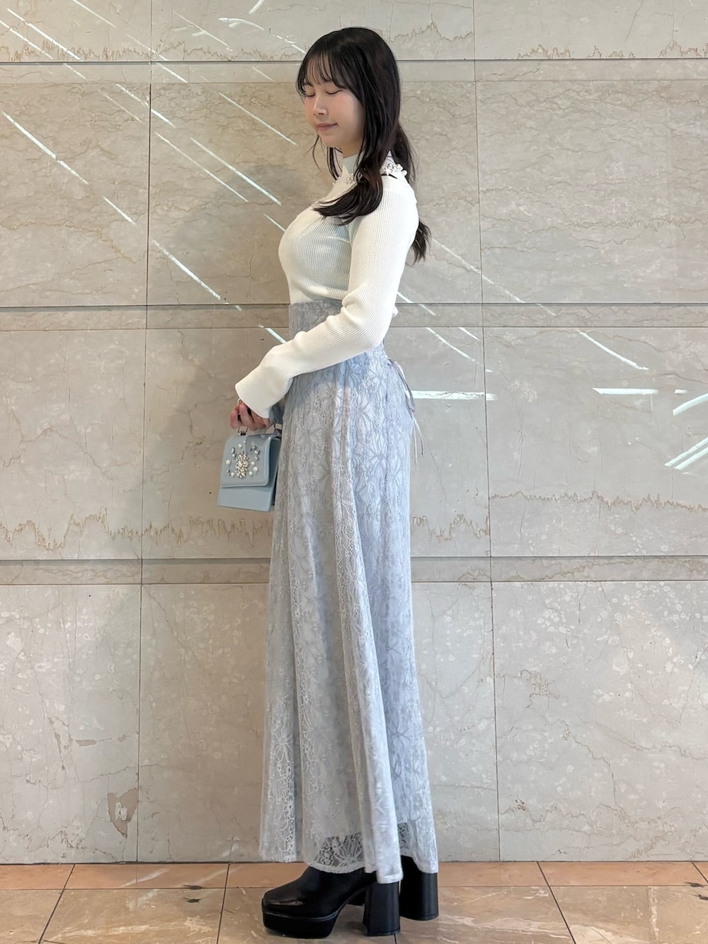 ブルー系のショルダーバッグ、ブラック系のブーツ、ブルー系のスカートを着用したレディースの冬コーディネートの2枚目の写真