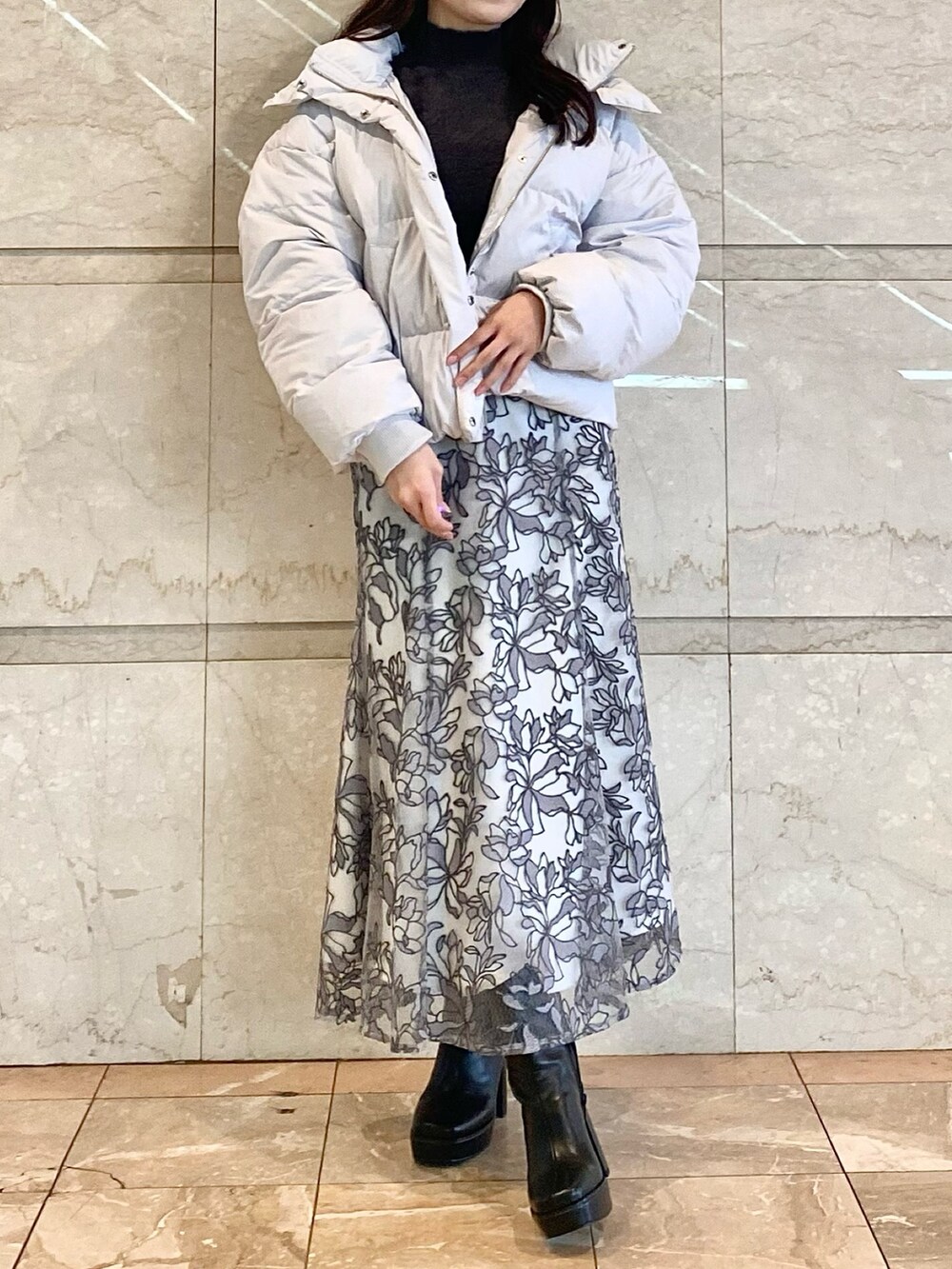 グレー系のスカート、グレー系のダウンジャケット/コート、グレー系のニット/セーターを着用したレディースの冬コーディネートの5枚目の写真