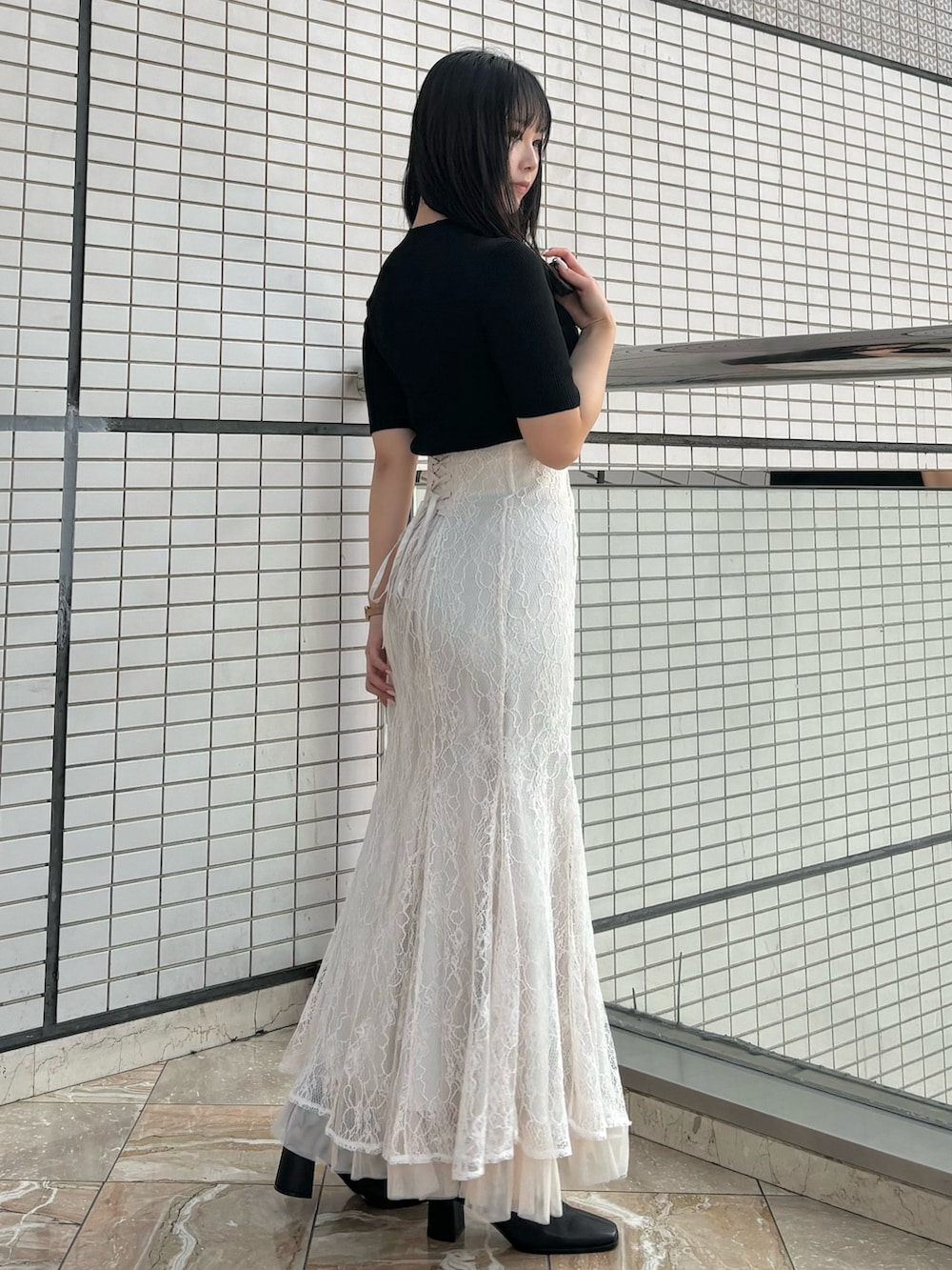 ホワイト系のスカート、ブラック系のブーツ、ブラック系のニット/セーターを着用したレディースの秋コーディネートの4枚目の写真