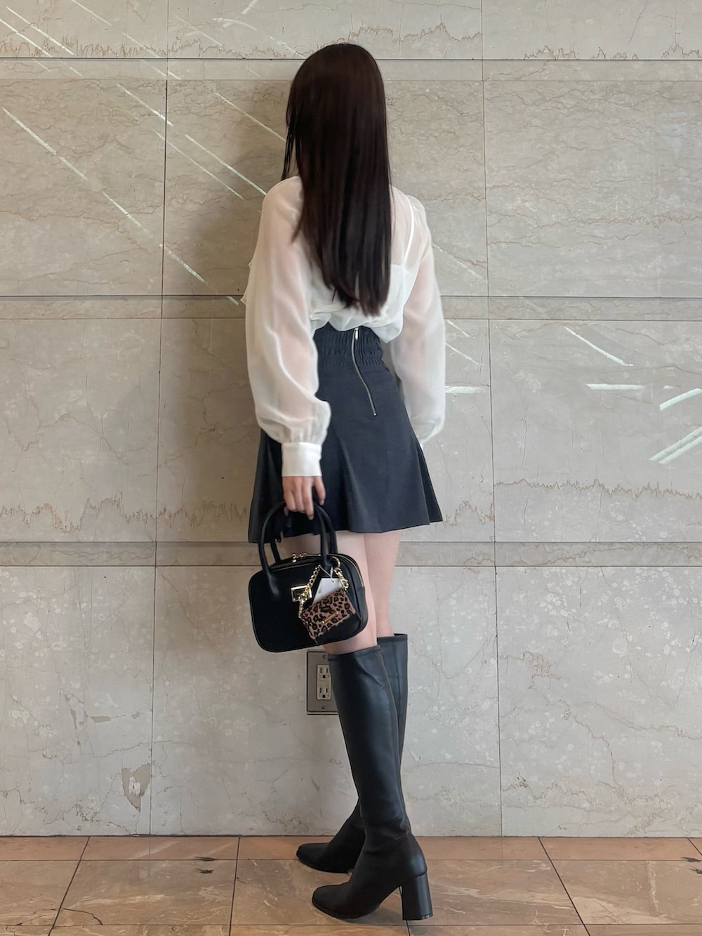グレー系のスカート、ブラック系のブーツ、ブラック系のハンドバッグを着用したレディースの秋コーディネートの5枚目の写真