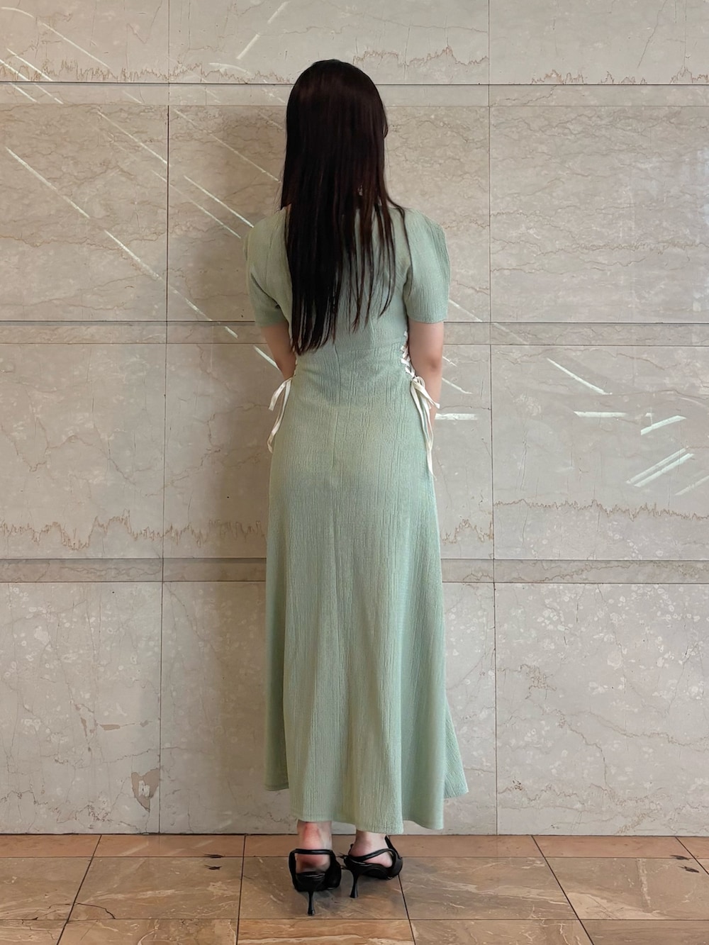 グリーン系のワンピース、ブラック系のパンプス、ホワイト系のショルダーバッグを着用したレディースの夏コーディネートの4枚目の写真