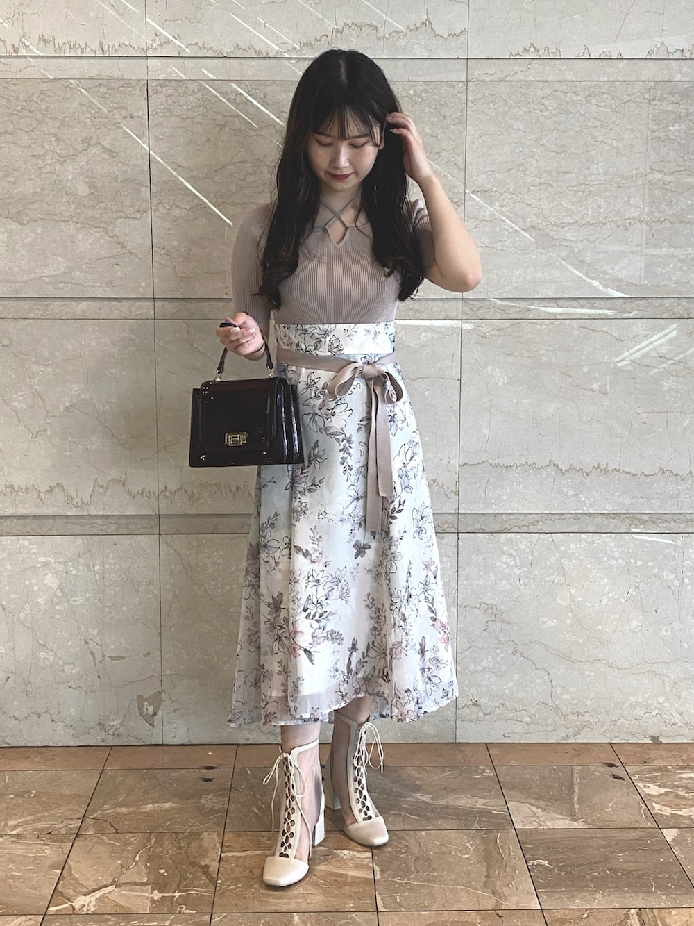 ベージュ系のワンピース、レッド系のハンドバッグ、ホワイト系のブーツを着用したレディースの夏コーディネートの2枚目の写真