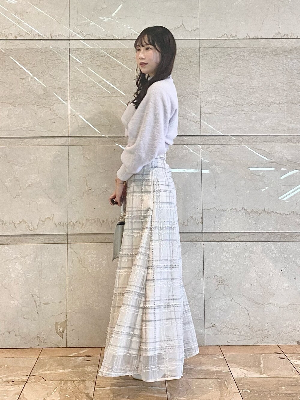 シルバー系のハンドバッグ、ホワイト系のブーツ、パープル系のニット/セーターを着用したレディースの冬コーディネートの2枚目の写真