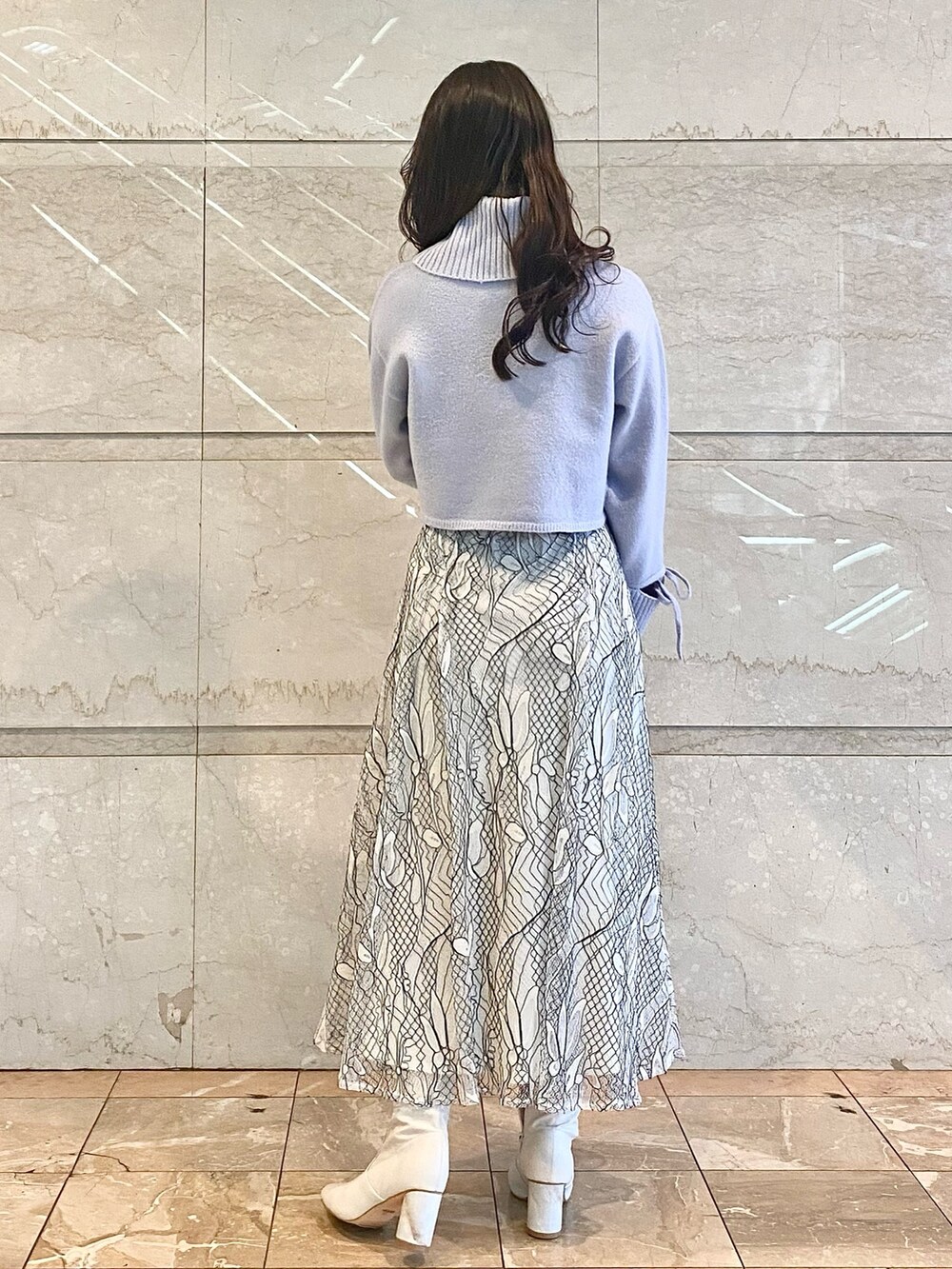 ホワイト系のスカート、ブルー系のニット/セーター、ホワイト系のブーツを着用したレディースの冬コーディネートの2枚目の写真