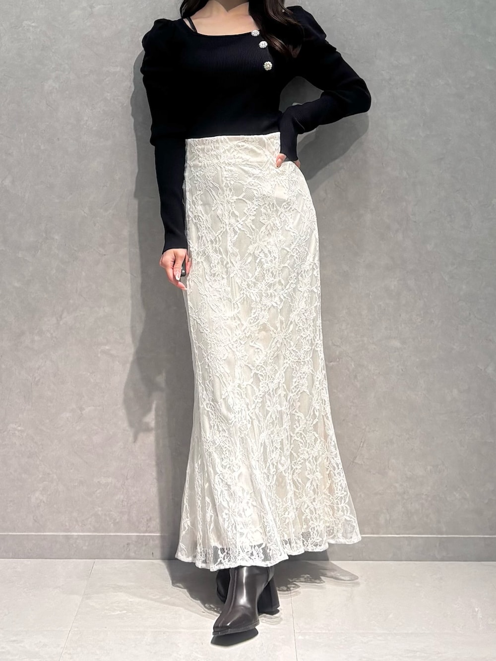 ホワイト系のスカート、ブルー系のニット/セーター、ブラウン系のブーツを着用したレディースの冬コーディネートの2枚目の写真