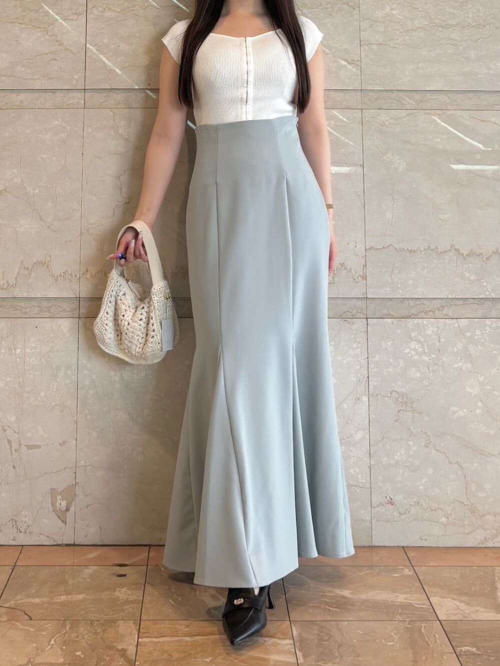 ブラック系のパンプス、ブルー系のスカート、ホワイト系のニット/セーターを着用したレディースの夏コーディネートの4枚目の写真