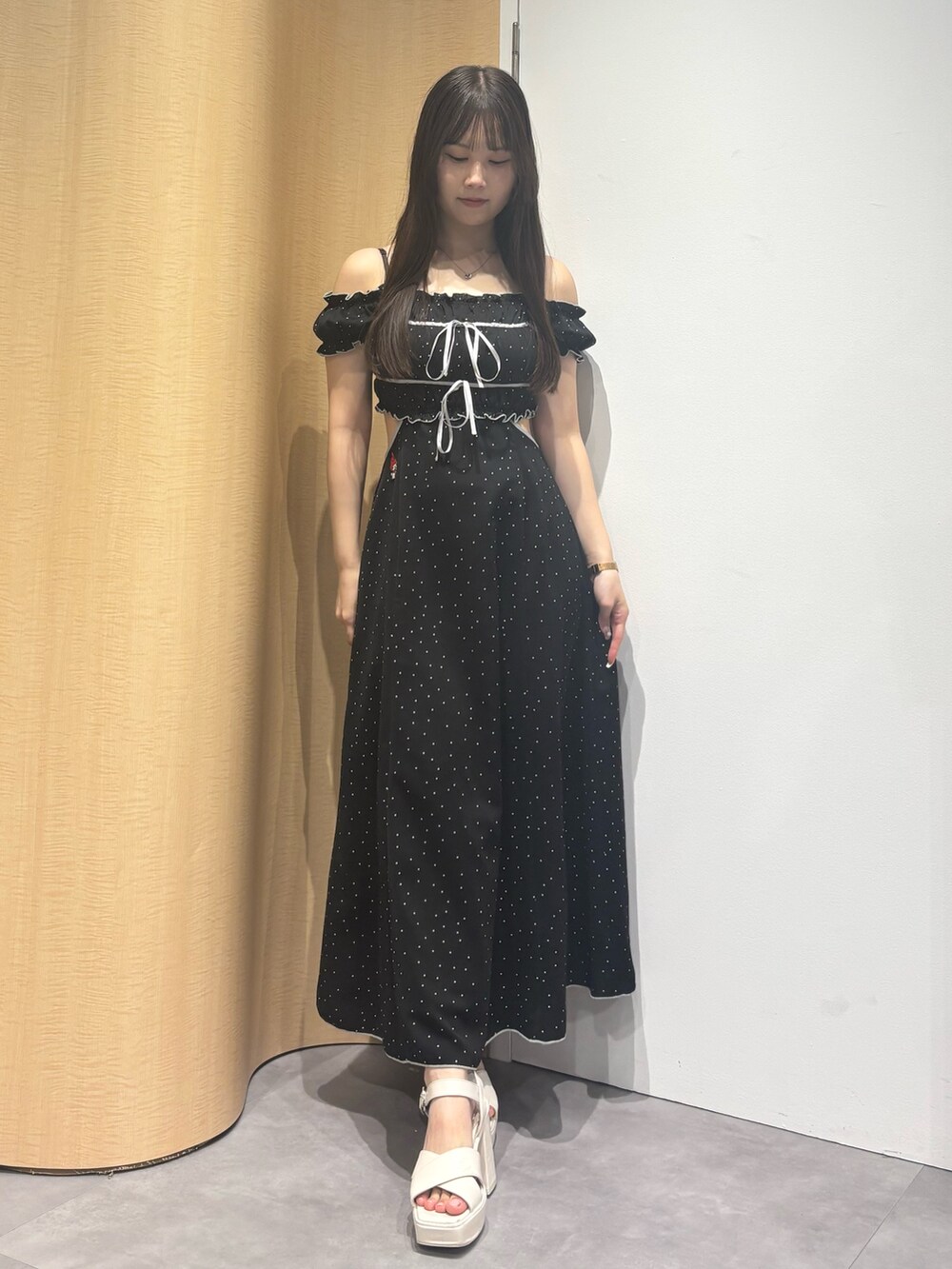 ホワイト系のサンダル、ブラック系のワンピースを着用したレディースの夏コーディネートの2枚目の写真