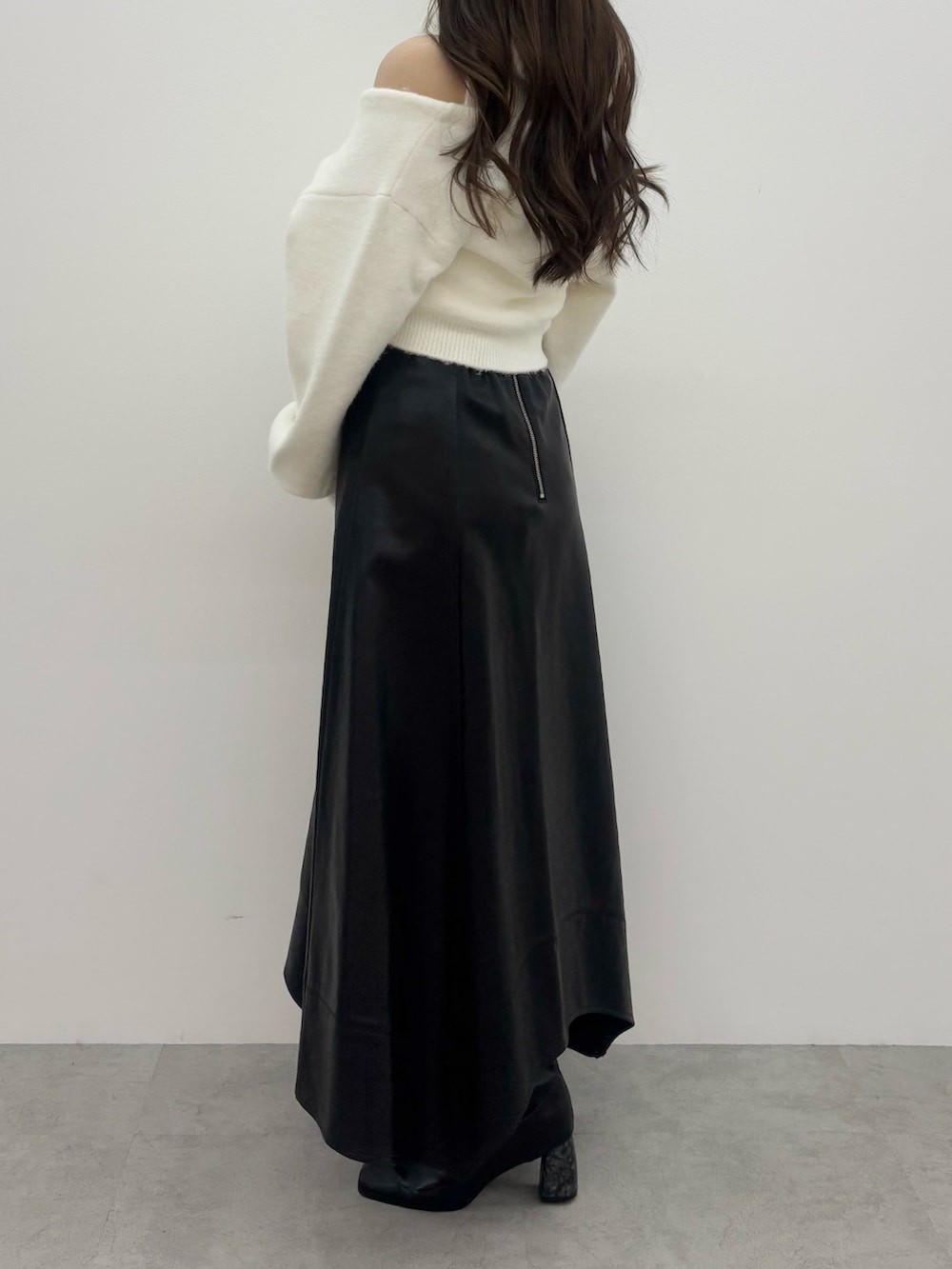 ホワイト系のニット/セーター、ブラック系のスカート、ブラック系のブーツを着用したレディースの冬コーディネートの2枚目の写真