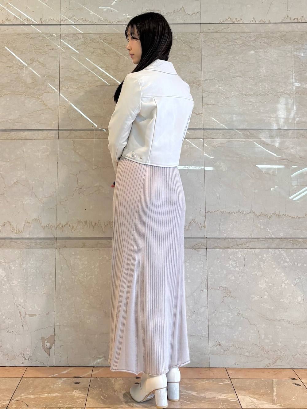 ピンク系のワンピース、ホワイト系のブーツ、ホワイト系のライダースジャケットを着用したレディースの冬コーディネートの3枚目の写真