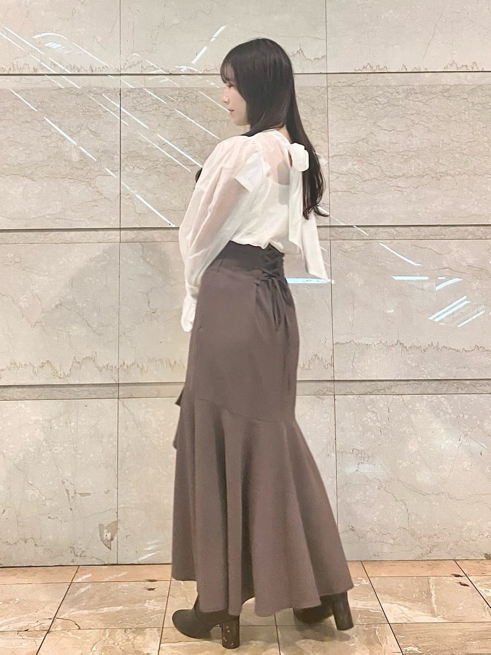 ブラウン系のスカート、ホワイト系のシャツ/ブラウス、ブラウン系のブーツを着用したレディースの冬コーディネートの4枚目の写真