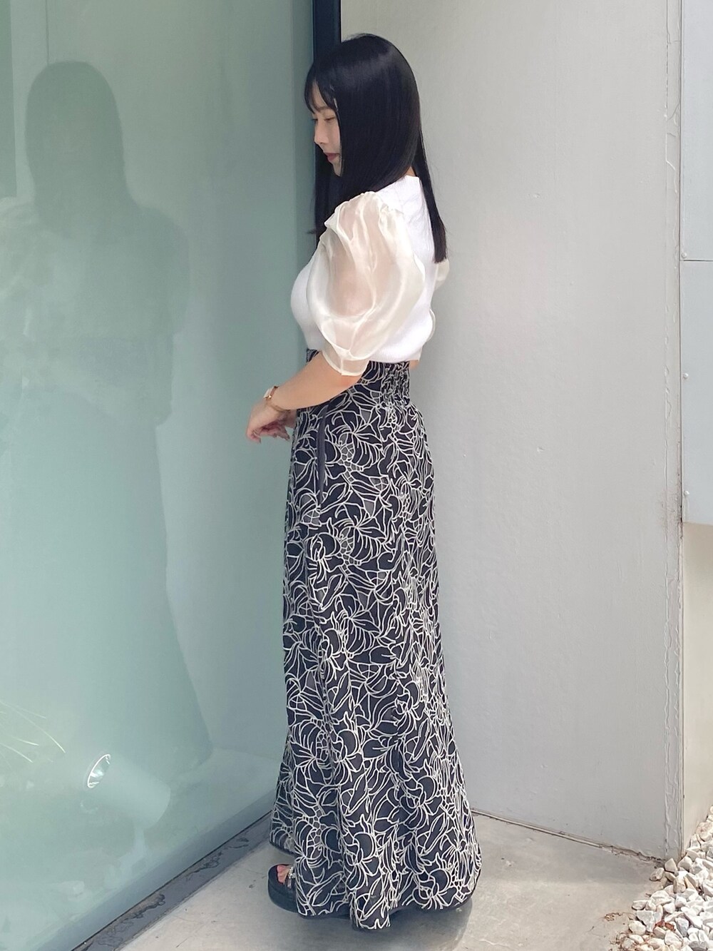 ブラック系のサンダル、ホワイト系のニット/セーター、ブラック系のスカートを着用したレディースの夏コーディネートの2枚目の写真