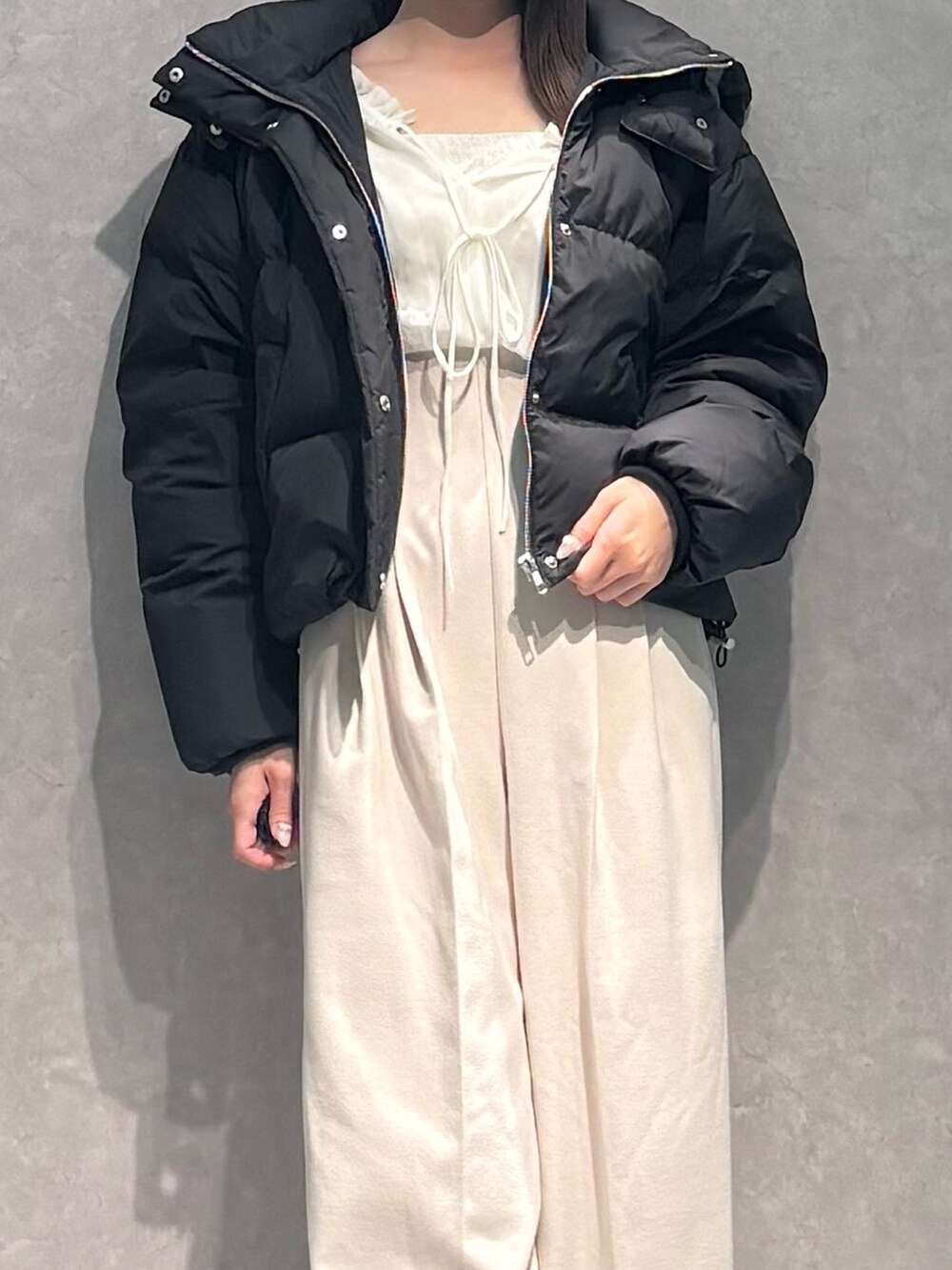 ホワイト系のワンピース、ブラック系のダウンジャケット/コート、ブラック系のブーツを着用したレディースの秋コーディネートの3枚目の写真