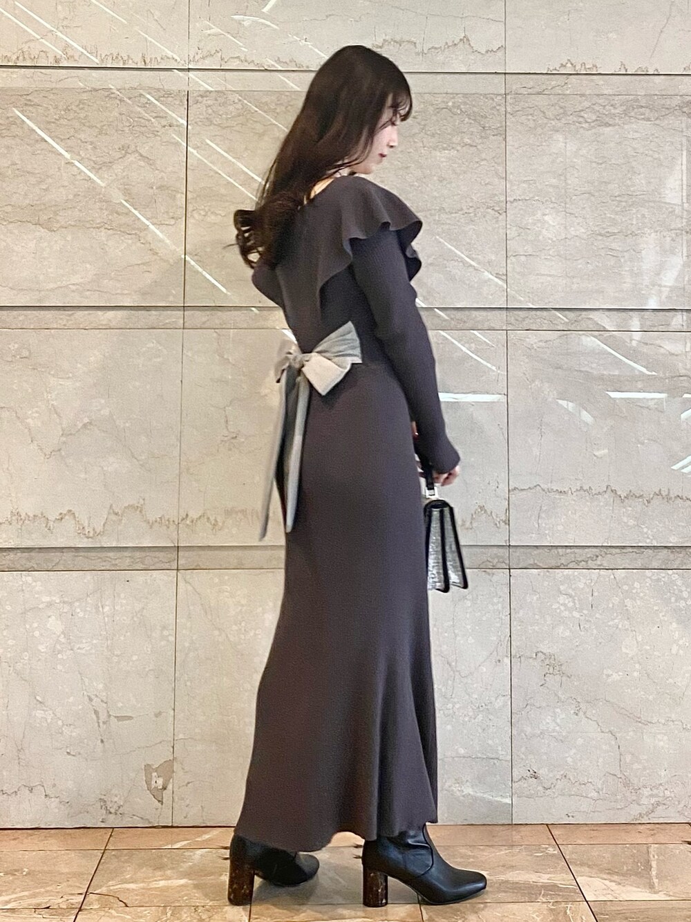 グレー系のワンピース、ブラック系のブーツ、ブラック系のハンドバッグを着用したレディースの冬コーディネートの4枚目の写真