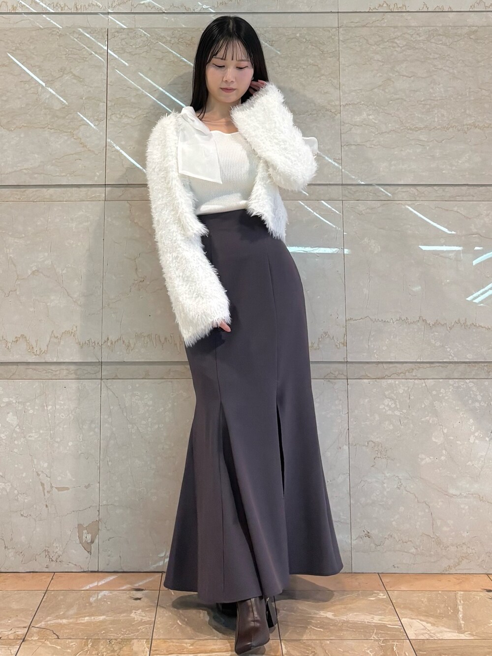 グレー系のスカート、ブラウン系のブーツ、ホワイト系のニット/セーターを着用したレディースの冬コーディネートの2枚目の写真