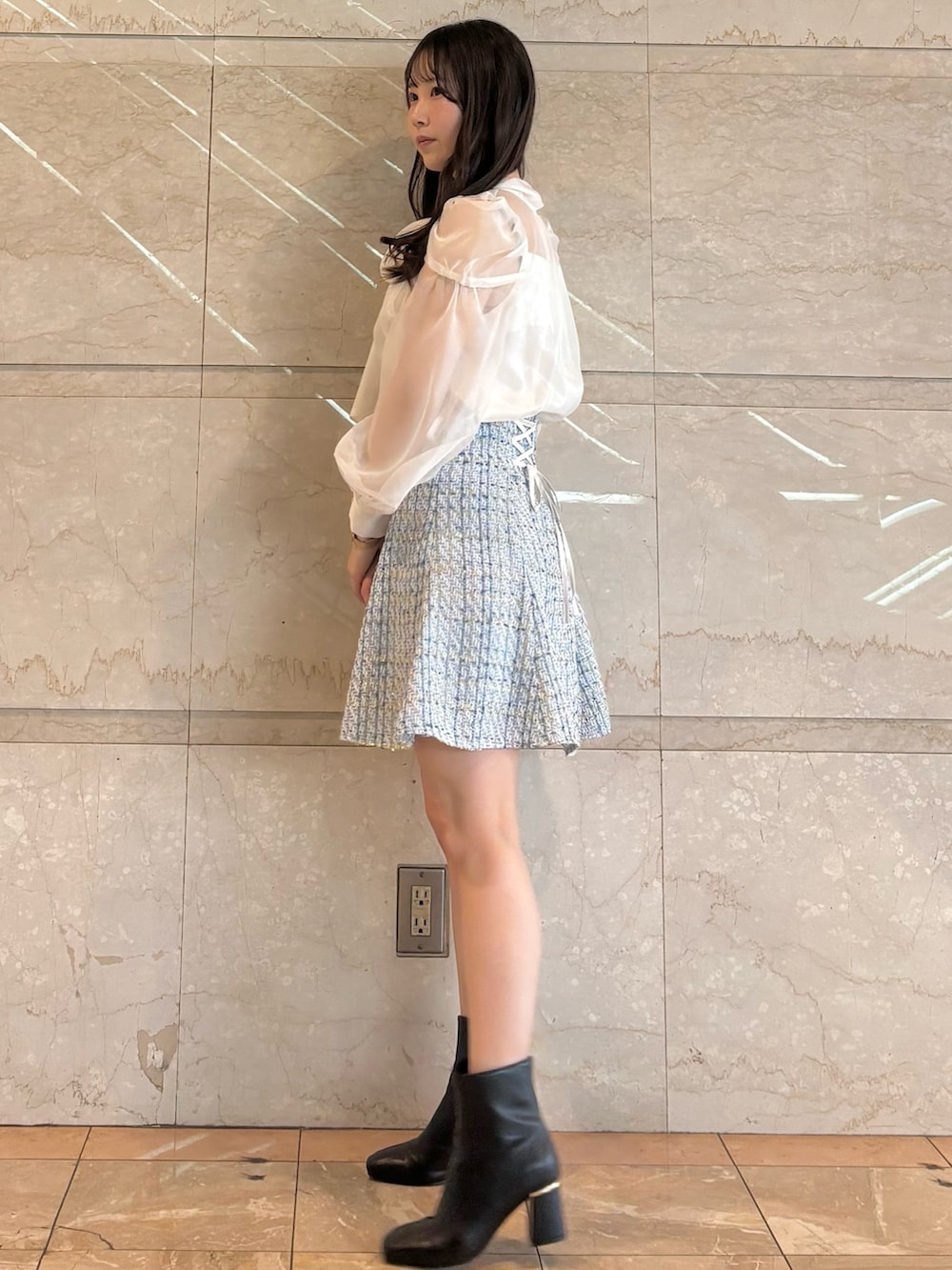 ブルー系のスカート、ホワイト系のシャツ/ブラウス、ブラック系のブーツを着用したレディースの冬コーディネートの2枚目の写真