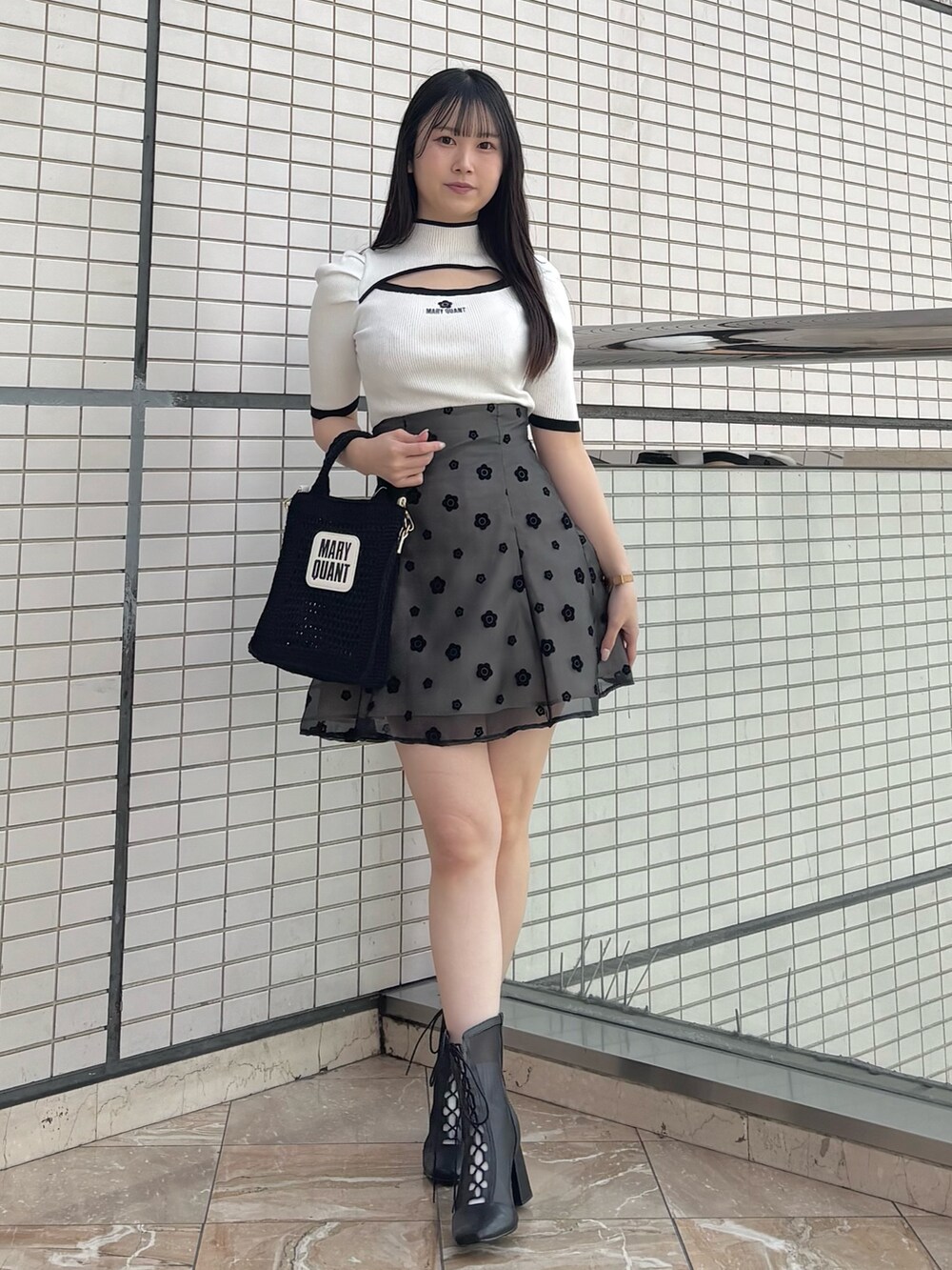 ブラック系のスカート、ブラック系のブーツ、ホワイト系のニット/セーターを着用したレディースの春コーディネートの2枚目の写真