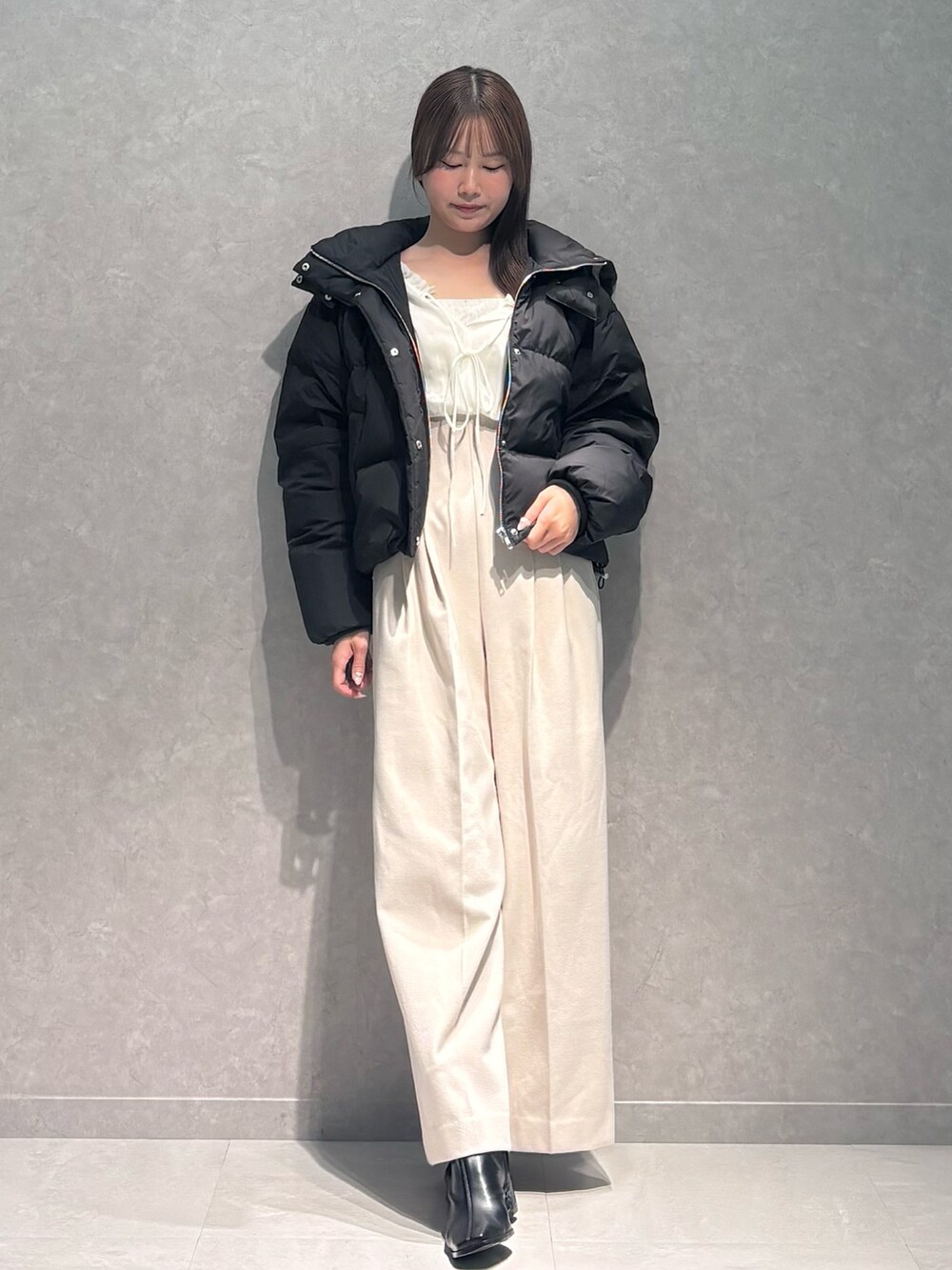 ホワイト系のワンピース、ブラック系のダウンジャケット/コート、ブラック系のブーツを着用したレディースの秋コーディネートの2枚目の写真