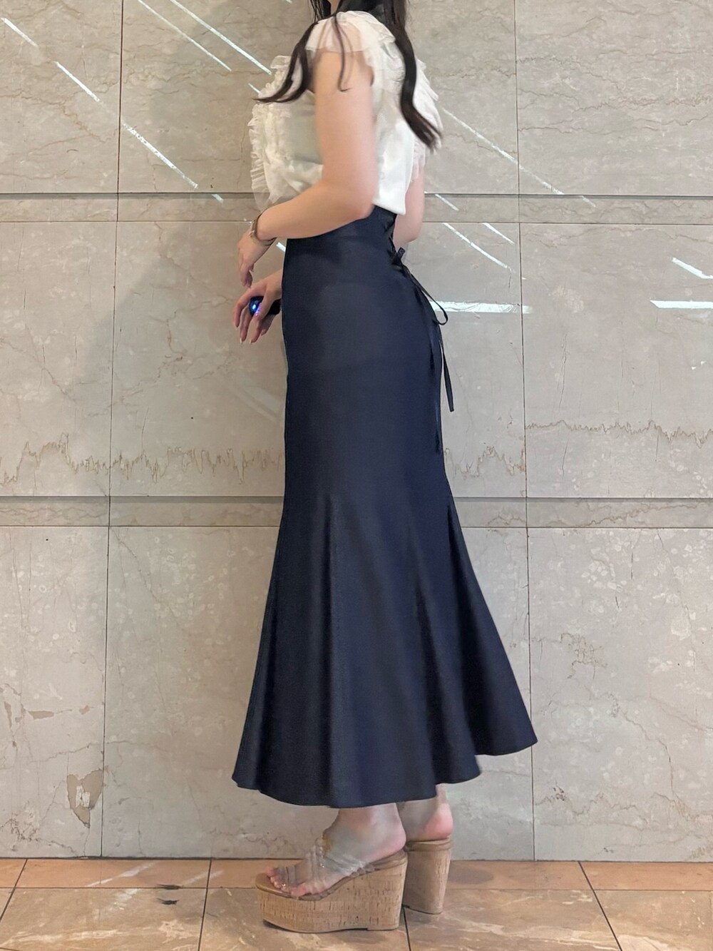 ブルー系のスカート、ホワイト系のニット/セーター、その他のサンダルを着用したレディースの春コーディネートの5枚目の写真