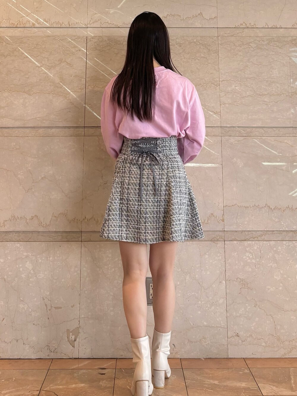 ブラック系のスカート、ホワイト系のブーツ、ピンク系のTシャツ/カットソーを着用したレディースの冬コーディネートの7枚目の写真
