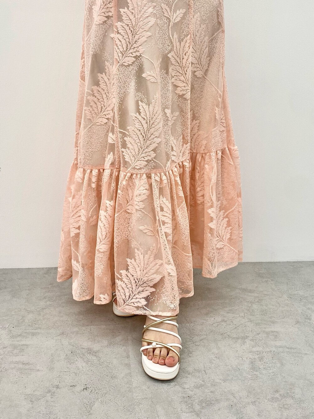 オレンジ系のワンピース、ホワイト系のサンダル、ホワイト系のカーディガン/ボレロを着用したレディースの春コーディネートの3枚目の写真