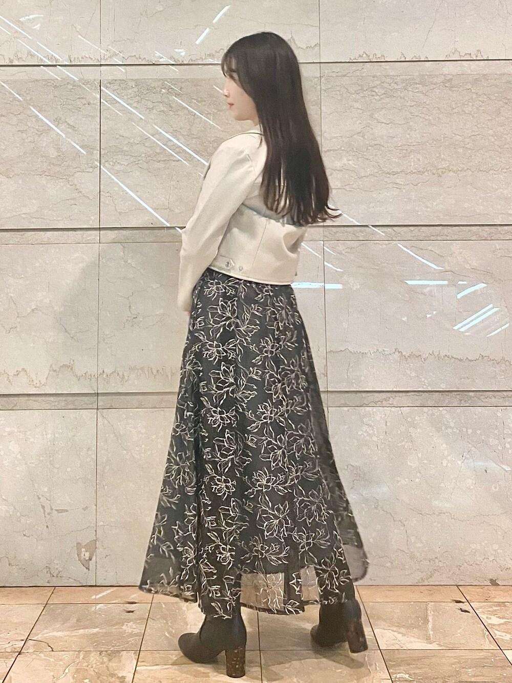 グレー系のスカート、ブラック系のニット/セーター、ホワイト系のライダースジャケットを着用したレディースの冬コーディネートの4枚目の写真