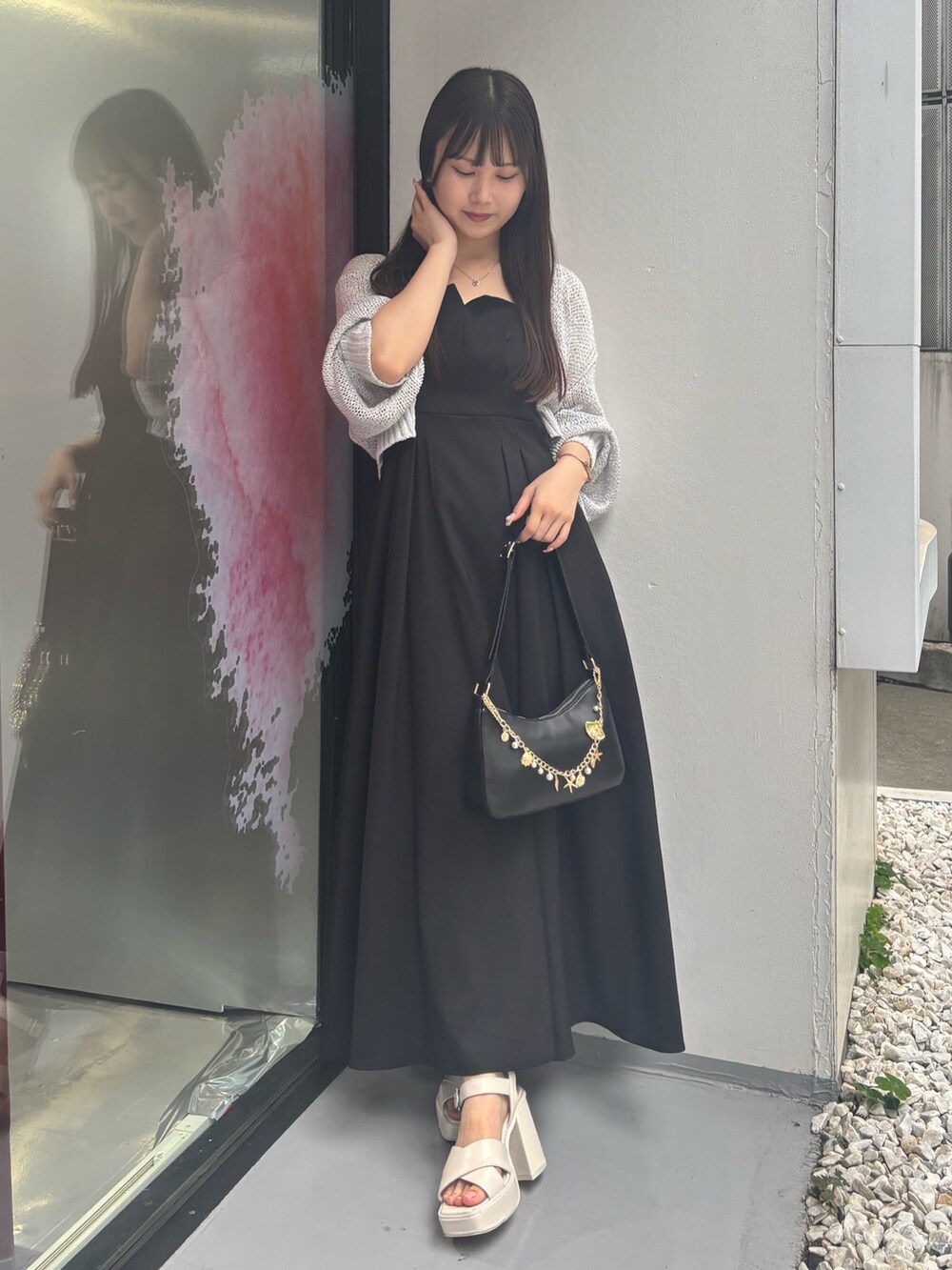 ブラック系のワンピース、ホワイト系のサンダル、ブラック系のハンドバッグを着用したレディースの夏コーディネートの2枚目の写真