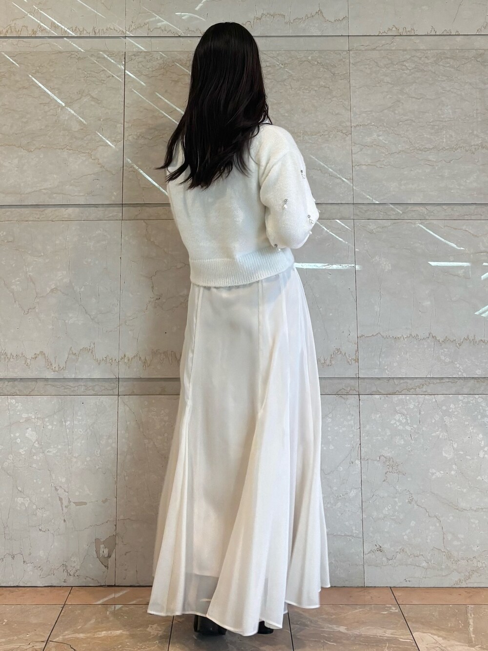 ホワイト系のスカート、ブラウン系のブーツ、ホワイト系のニット/セーターを着用したレディースの冬コーディネートの2枚目の写真
