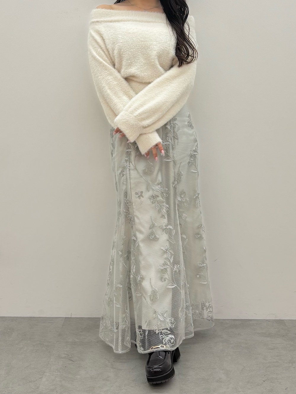 ホワイト系のニット/セーター、ブラウン系のブーツ、グリーン系のスカートを着用したレディースの秋コーディネートの2枚目の写真