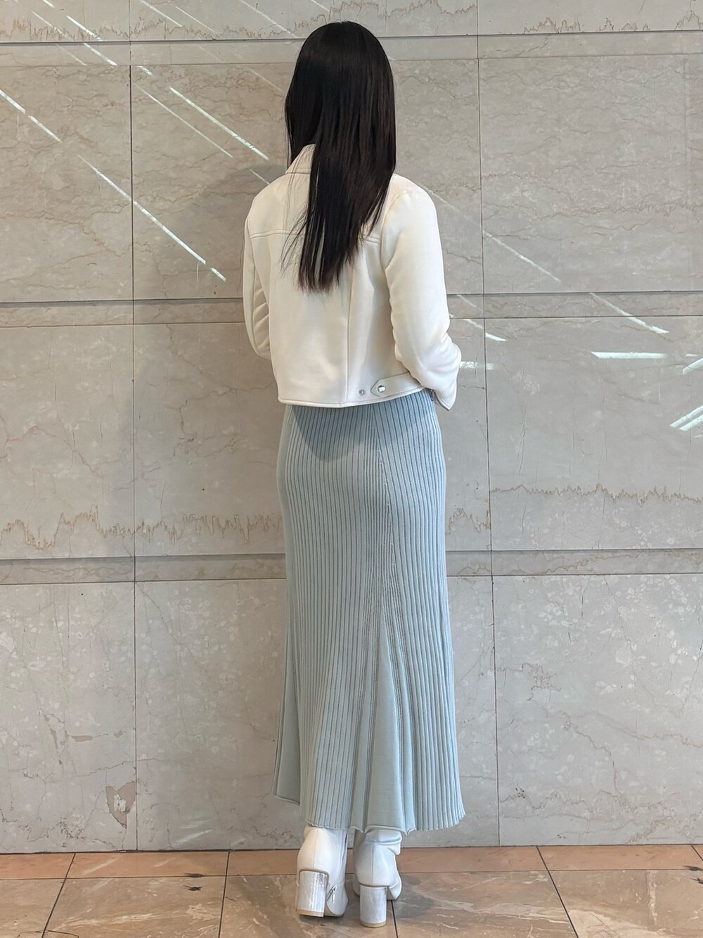 ブルー系のワンピース、ホワイト系のブーツ、ホワイト系のライダースジャケットを着用したレディースの冬コーディネートの4枚目の写真