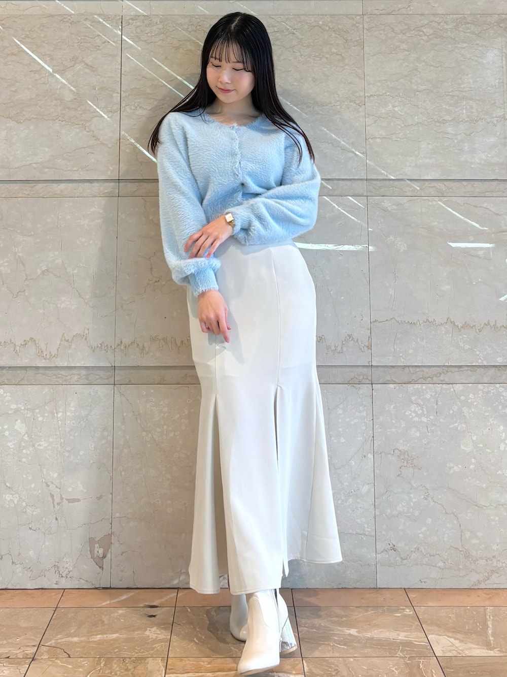 ホワイト系のブーツ、ブルー系のカーディガン/ボレロ、ホワイト系のスカートを着用したレディースの冬コーディネートの2枚目の写真