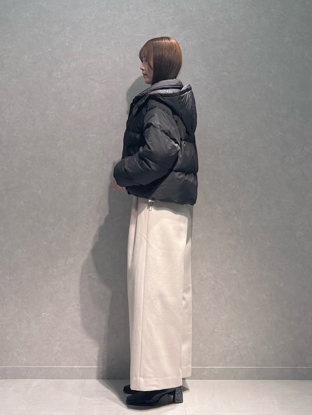 ホワイト系のワンピース、ブラック系のダウンジャケット/コート、ブラック系のブーツを着用したレディースの秋コーディネートの5枚目の写真