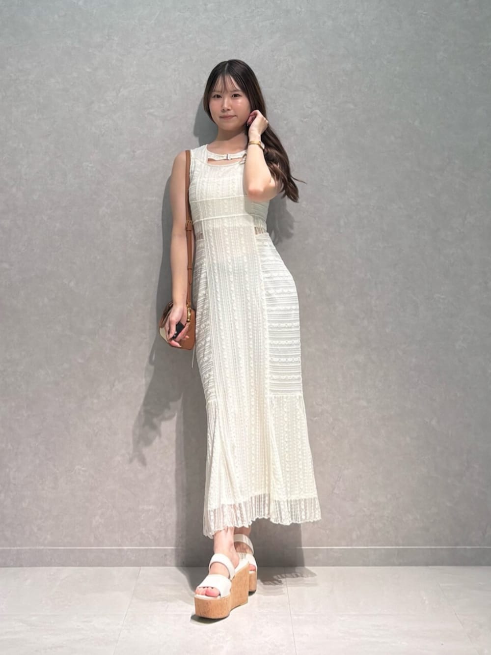 ブラウン系のハンドバッグ、ホワイト系のサンダル、ホワイト系のワンピースを着用したレディースの夏コーディネートの2枚目の写真