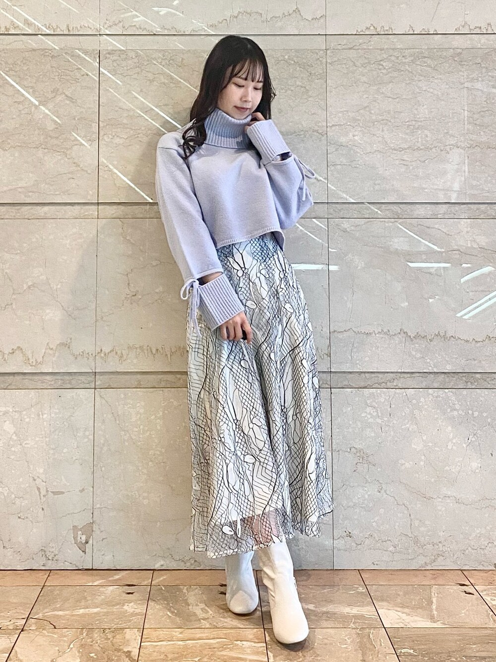 ホワイト系のスカート、ブルー系のニット/セーター、ホワイト系のブーツを着用したレディースの冬コーディネートの5枚目の写真