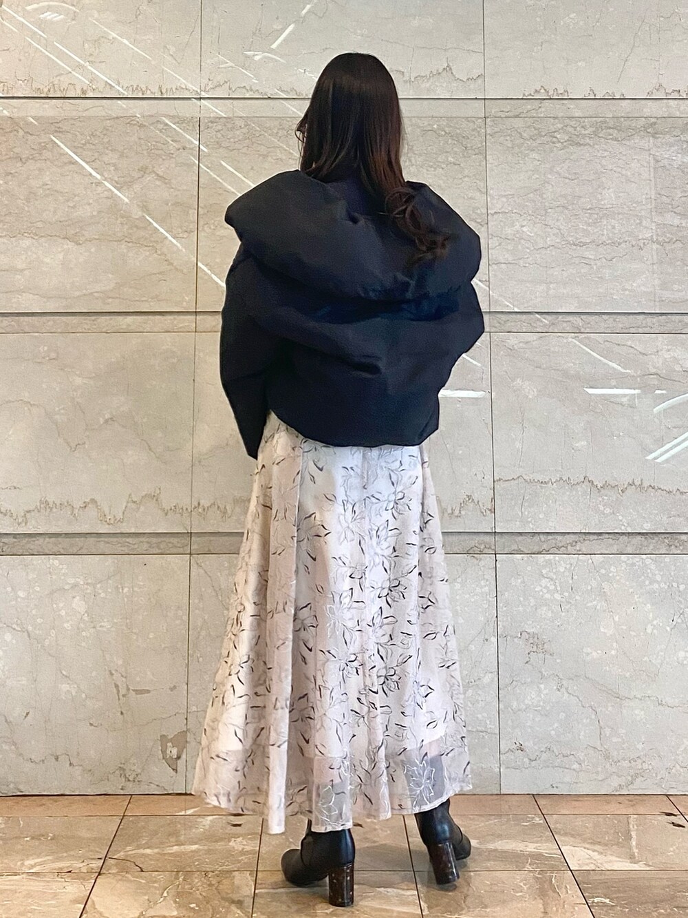 ベージュ系のスカート、グレー系のニット/セーター、ブラック系のダウンジャケット/コートを着用したレディースの冬コーディネートの3枚目の写真