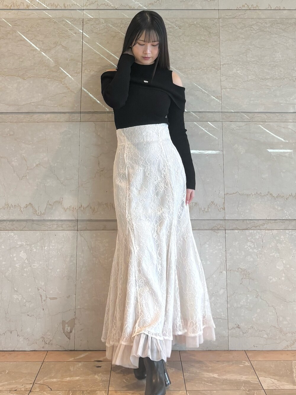 ホワイト系のスカート、ブラック系のブーツ、ブラック系のニット/セーターを着用したレディースの冬コーディネートの4枚目の写真