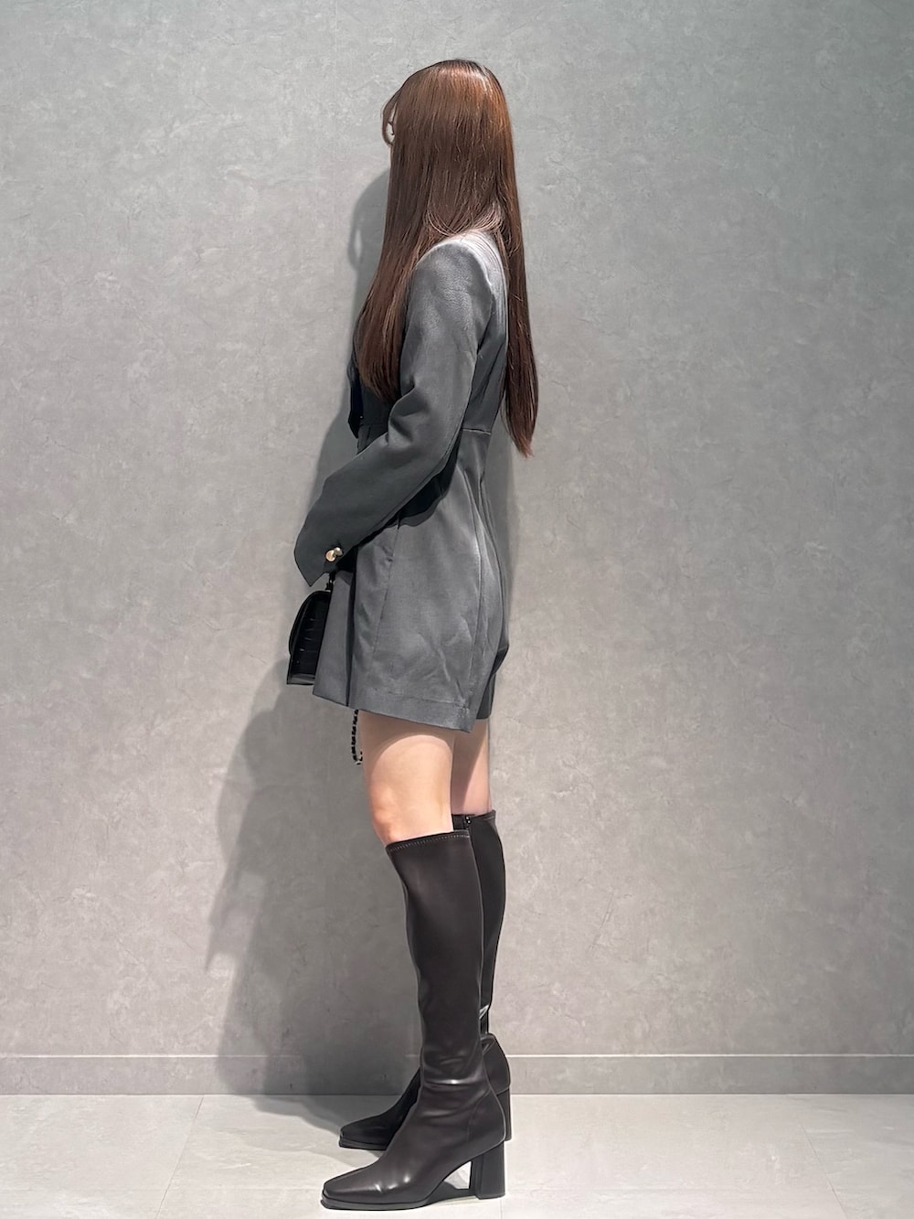 グレー系のつなぎ/オールインワン、ブラウン系のブーツ、ブラック系のハンドバッグを着用したレディースの冬コーディネートの5枚目の写真