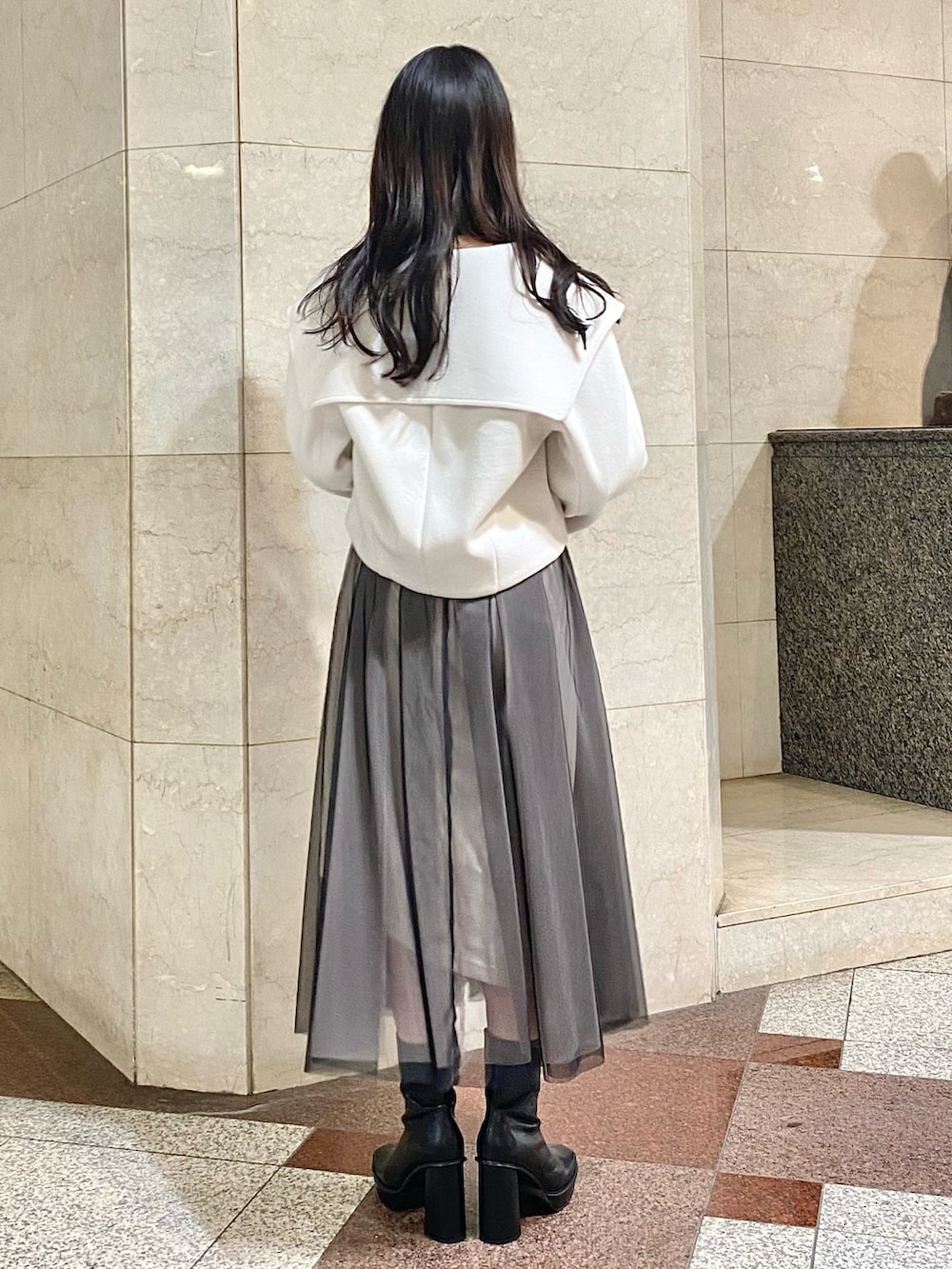 ブラック系のワンピース、ホワイト系のその他アウター、ブラック系のブーツを着用したレディースの秋コーディネートの3枚目の写真