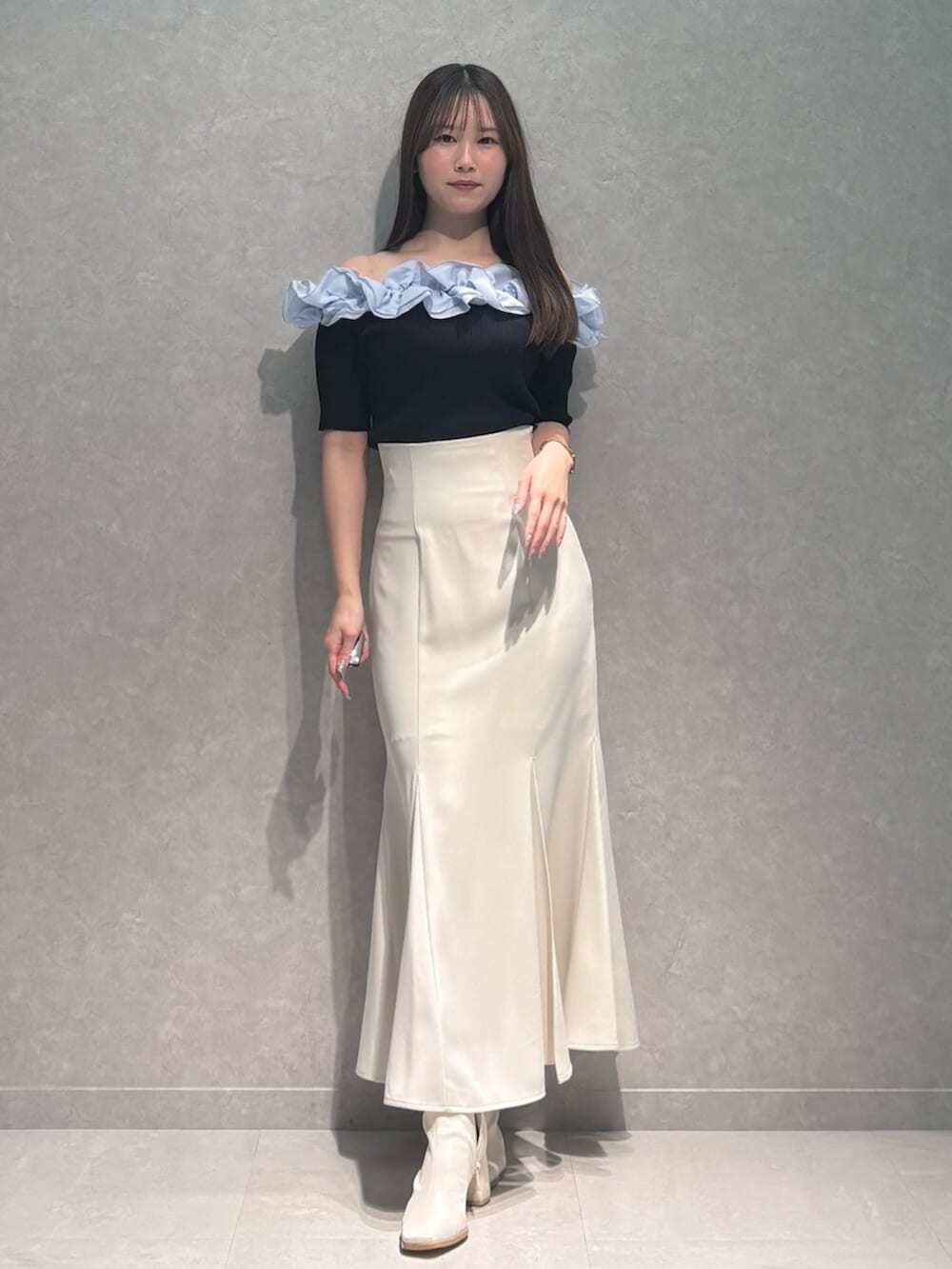 ホワイト系のブーツ、ホワイト系のスカート、ブルー系のニット/セーターを着用したレディースの春コーディネートの2枚目の写真