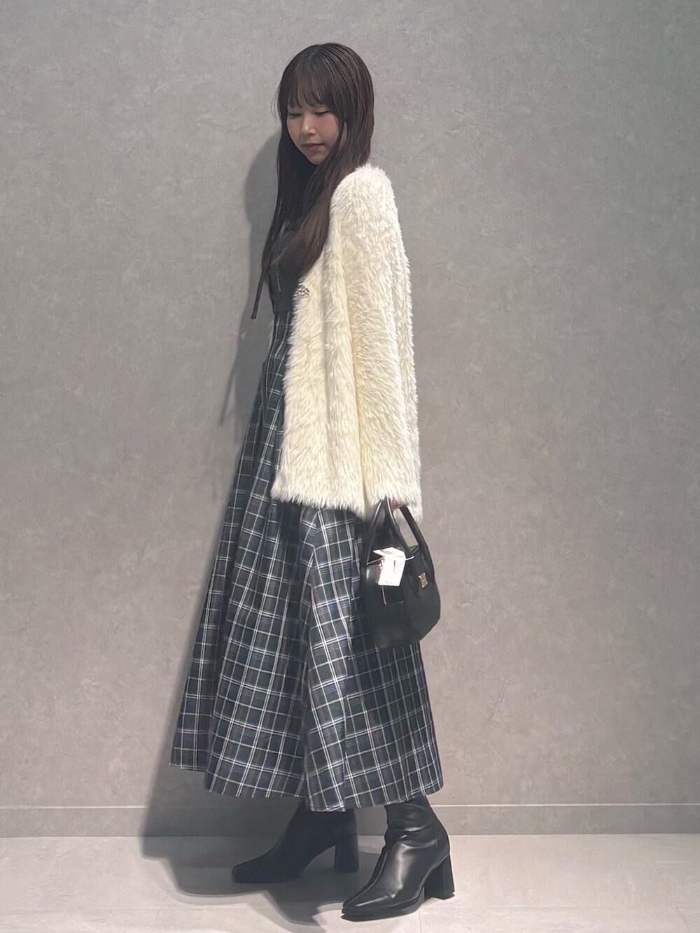 グリーン系のワンピース、ブラック系のハンドバッグ、ブラック系のブーツを着用したレディースの秋コーディネートの4枚目の写真