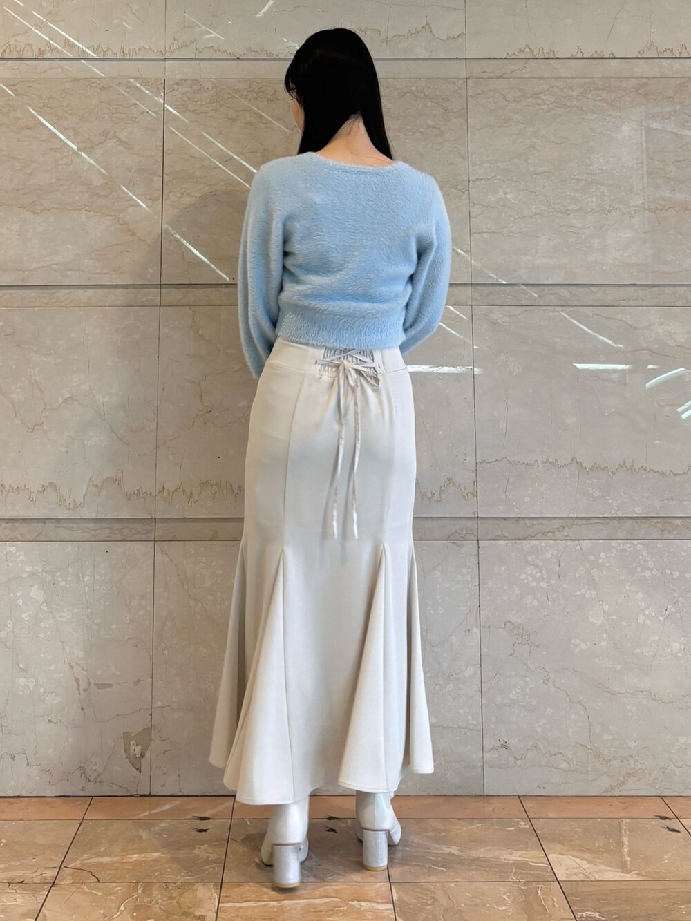 ホワイト系のブーツ、ブルー系のカーディガン/ボレロ、ホワイト系のスカートを着用したレディースの冬コーディネートの5枚目の写真