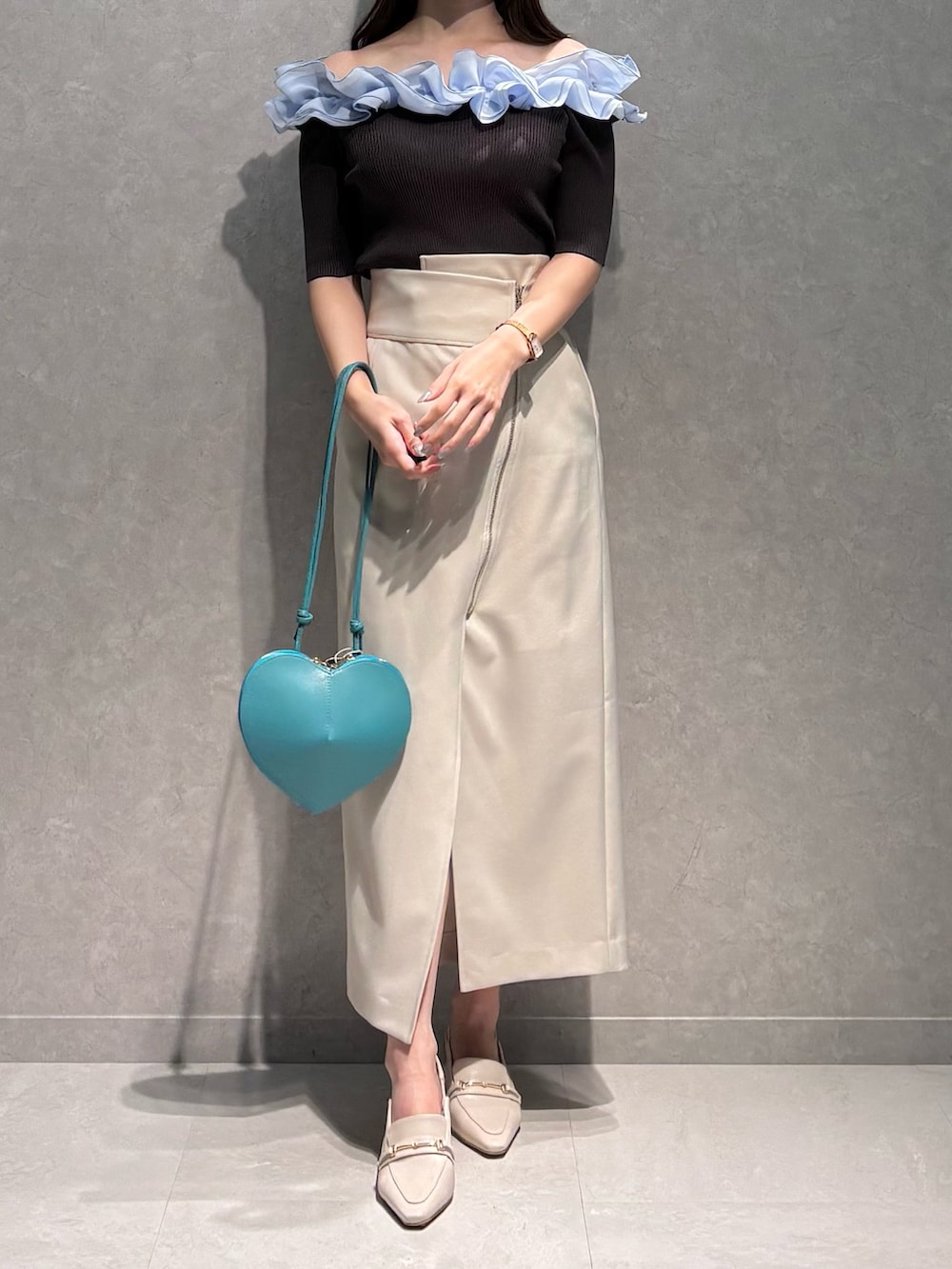 ホワイト系のスカート、グレー系のニット/セーター、グリーン系のショルダーバッグを着用したレディースの春コーディネートの3枚目の写真