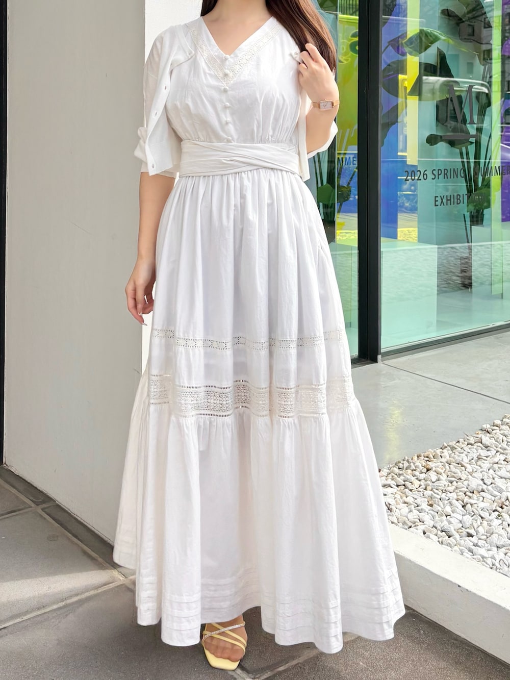 ホワイト系のワンピース、ホワイト系のカーディガン/ボレロ、イエロー系のサンダルを着用したレディースの春コーディネートの2枚目の写真