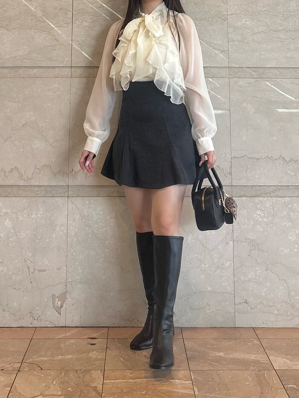 グレー系のスカート、ブラック系のブーツ、ブラック系のハンドバッグを着用したレディースの秋コーディネートの4枚目の写真