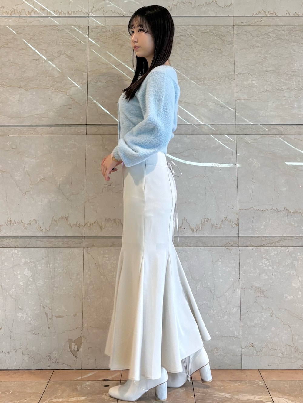 ホワイト系のブーツ、ブルー系のカーディガン/ボレロ、ホワイト系のスカートを着用したレディースの冬コーディネートの3枚目の写真