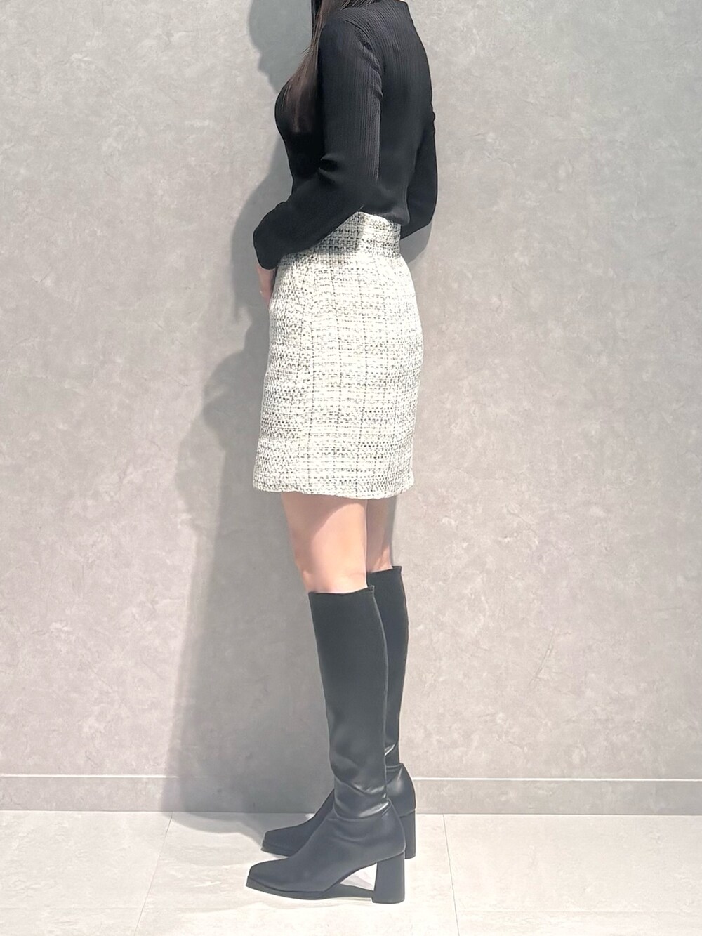 ホワイト系のスカート、ブラウン系のニット/セーター、ブラック系のブーツを着用したレディースの秋コーディネートの5枚目の写真