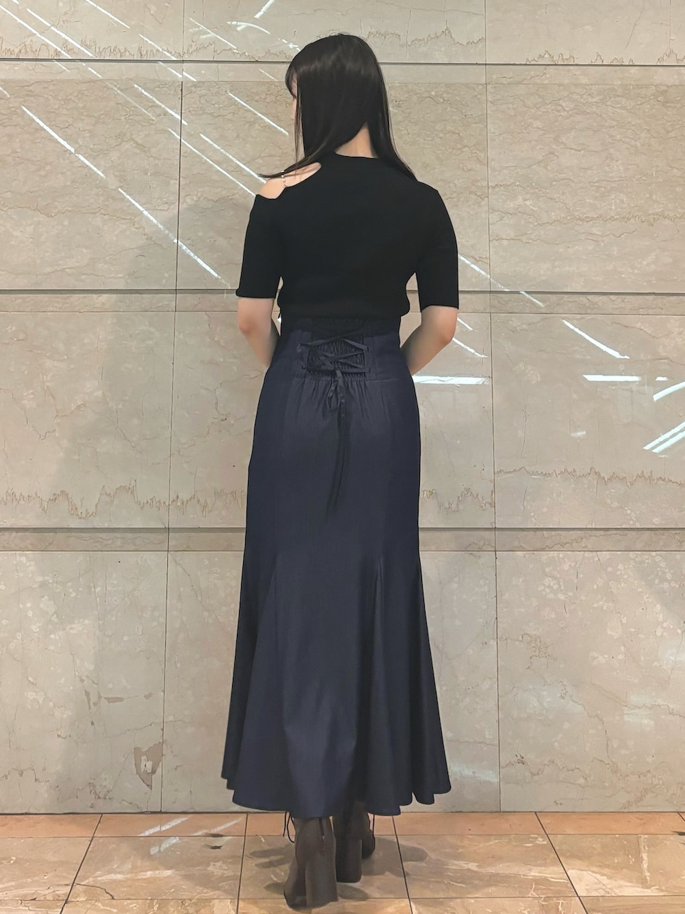 ブルー系のスカート、ブラウン系のブーツ、ブラック系のニット/セーターを着用したレディースの秋コーディネートの3枚目の写真